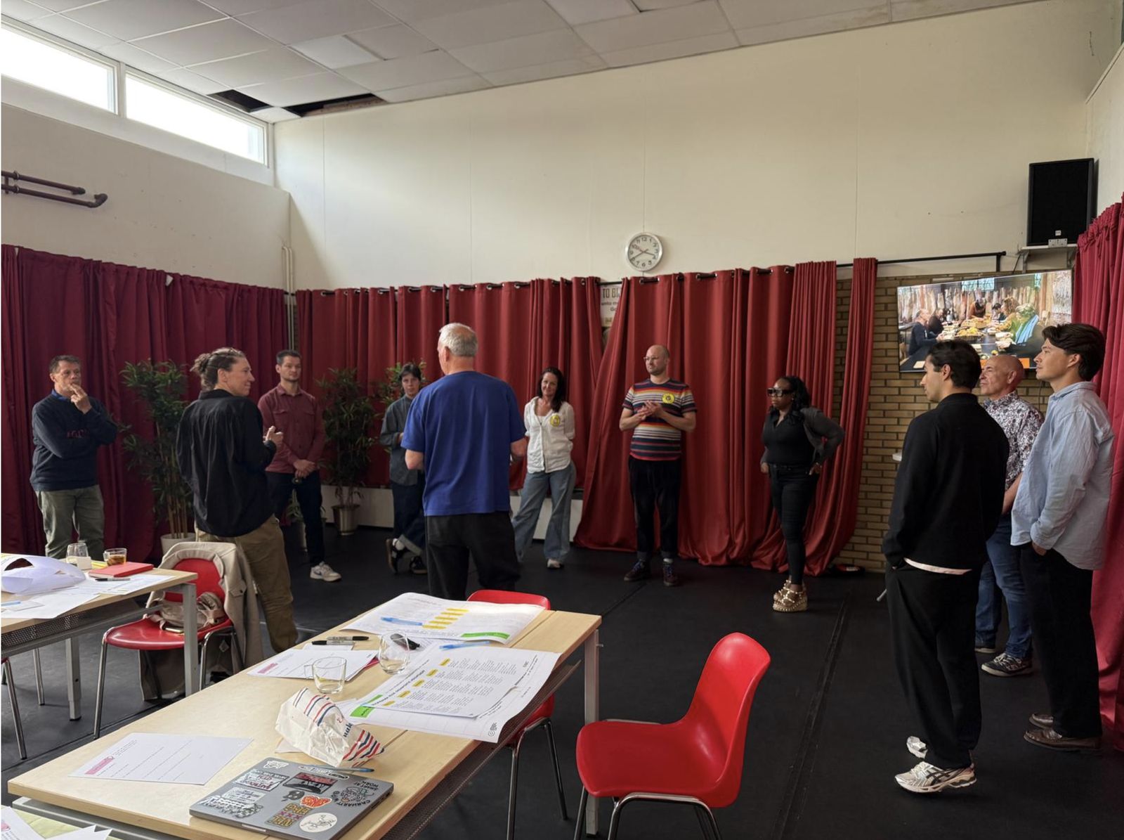 Participants of the first Living Lab standing in a circle in a workshop room, listening to each other during the opening exercise.